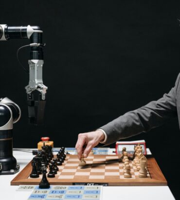 A bearded man strategically moves chess pieces while an AI robot arm assists in a futuristic game.